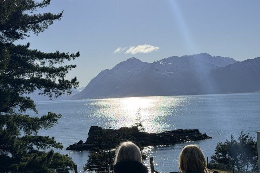 A lake with mountains in the background, a rocky outcrop in the water, and trees framing the scene. 3