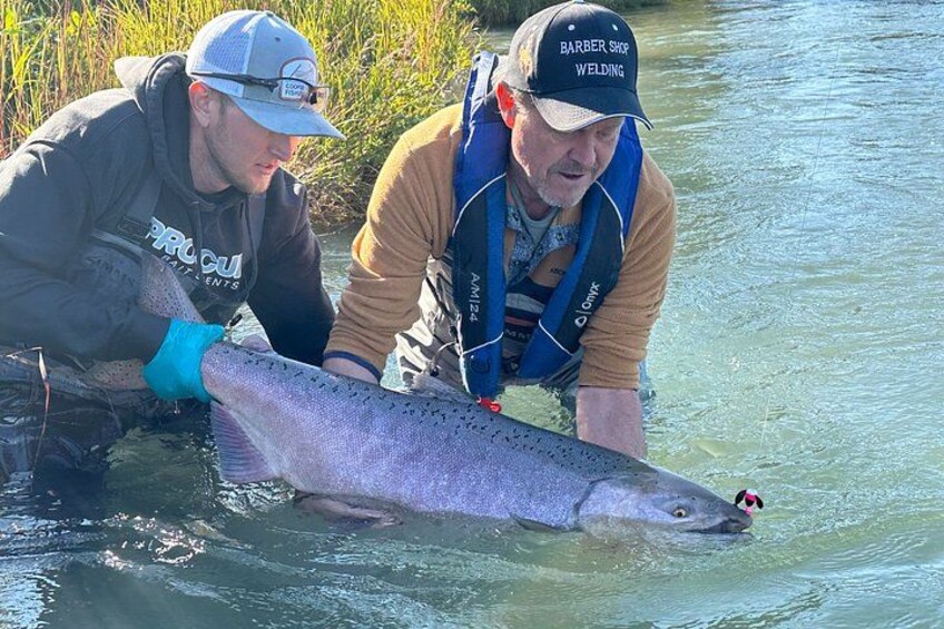 Two people holding a large fish in a river. 5