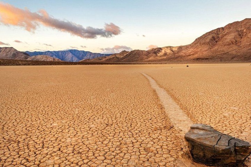 A vast salt flat with a wooden log in the foreground and mountains in the background. 4