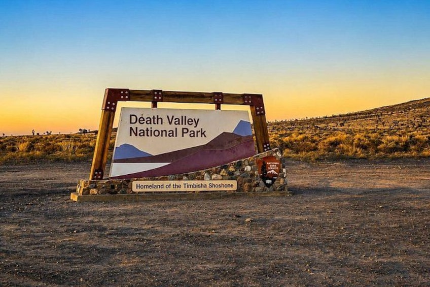A sign for Death Valley National Park with a desert landscape in the background. 2