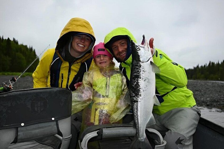 Three people on a boat holding a fish. 5