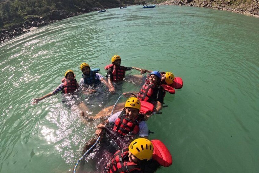 A group of people in a river wearing life jackets and helmets. 1