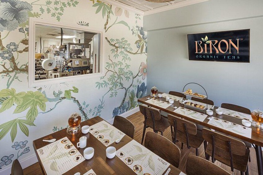 A restaurant interior with a floral mural, a dining table set for a meal, and a sign for 'BIRON Organic Teas'. 2