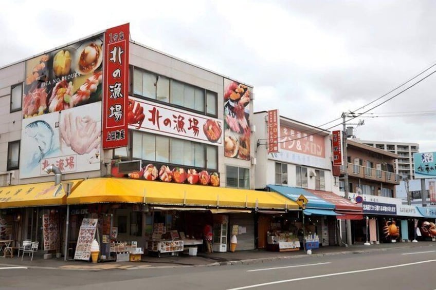 A street with a row of shops, including a restaurant with a large sign advertising food. 4
