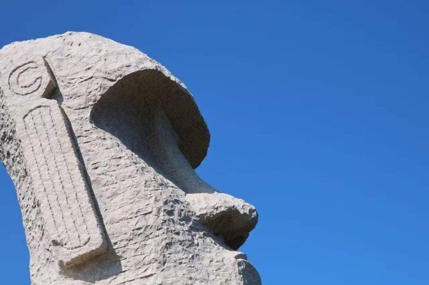 A stone sculpture with a carved face and a spiral symbol. 5