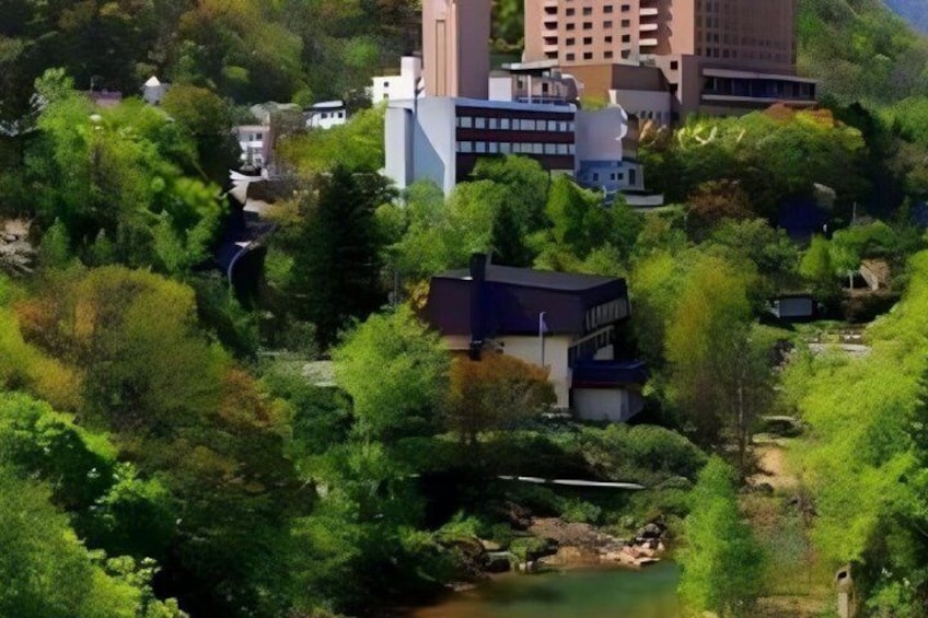 A lush green landscape with a river, buildings, and a hill in the background. 3