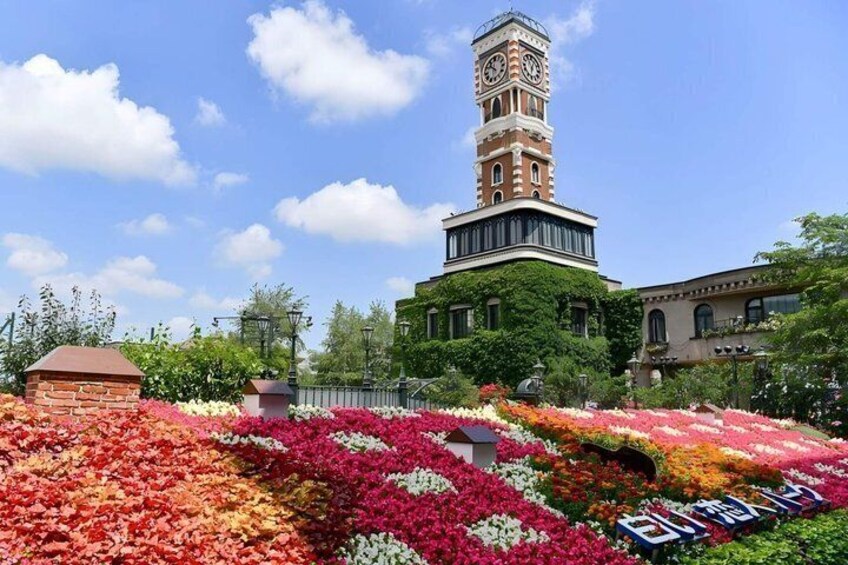 A tower with a clock, surrounded by a garden with colorful flowers. 1