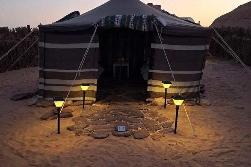 A tent with a striped awning, two lanterns, and a stone pathway leading to the entrance. 3