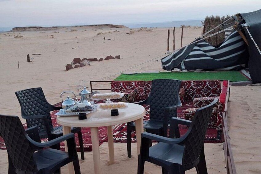A beachside dining setup with a table and chairs, a striped canopy, and a sandy beach in the background. 4