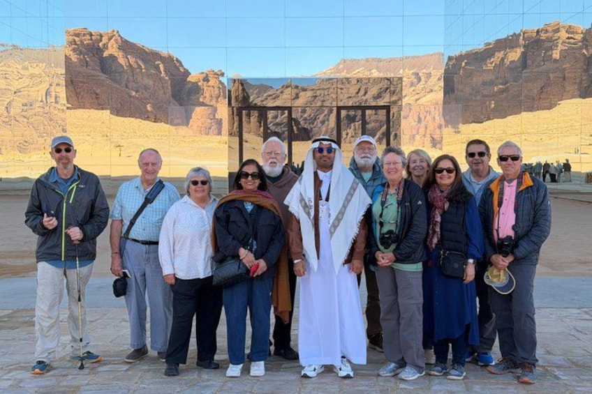 Eine Gruppe von Menschen steht vor einer großen Felsformation unter blauem Himmel. 1