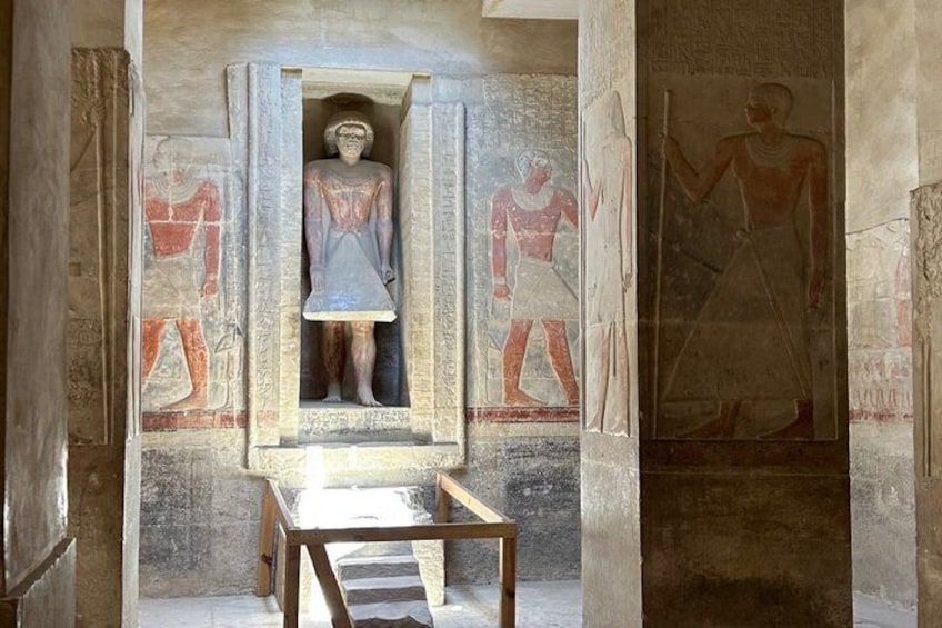 An ancient Egyptian tomb with a sarcophagus, wall paintings, and a wooden table. 1