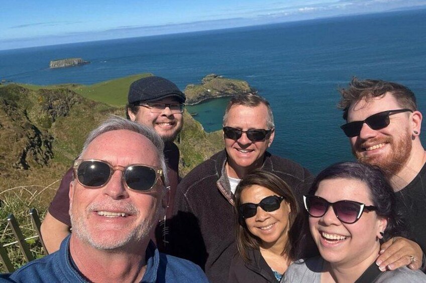 A group of people standing on a cliff overlooking the ocean. 4