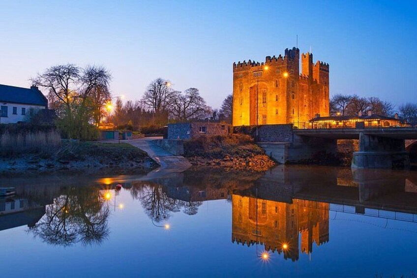 A castle at dusk with lights reflecting on a calm river. 2