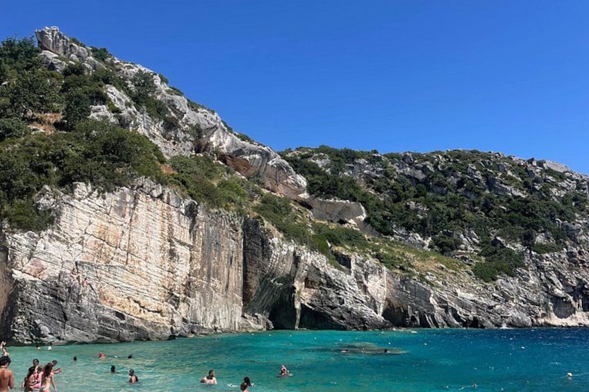 A coastal cliff with people swimming in the water. 5