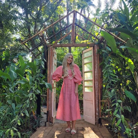 A person standing in a garden with a wooden archway and lush greenery. 2