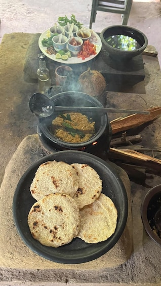 A traditional meal setup with flatbreads, a pot of stew, and a plate with various condiments. 4