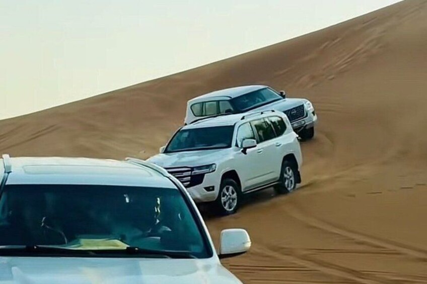 Two white SUVs on a sandy dune. 3