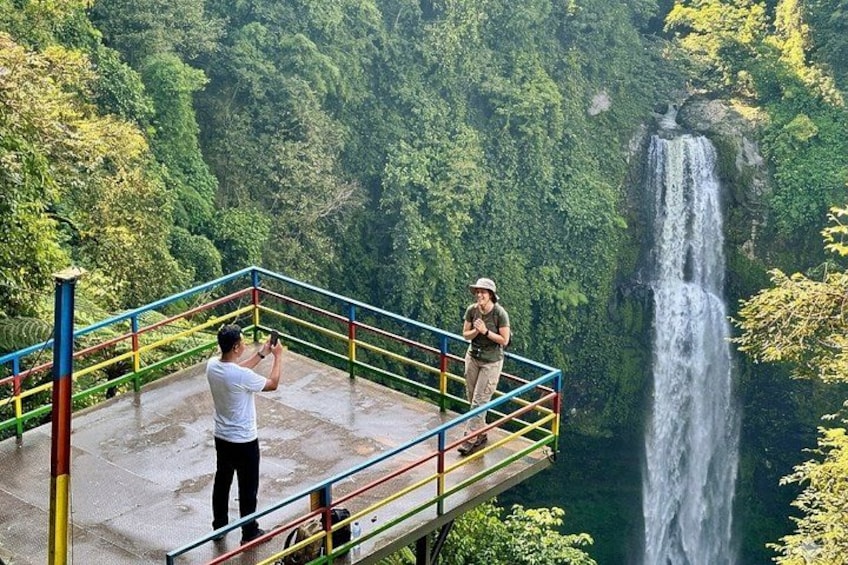 A person taking a photo of a waterfall from a viewing platform. 2