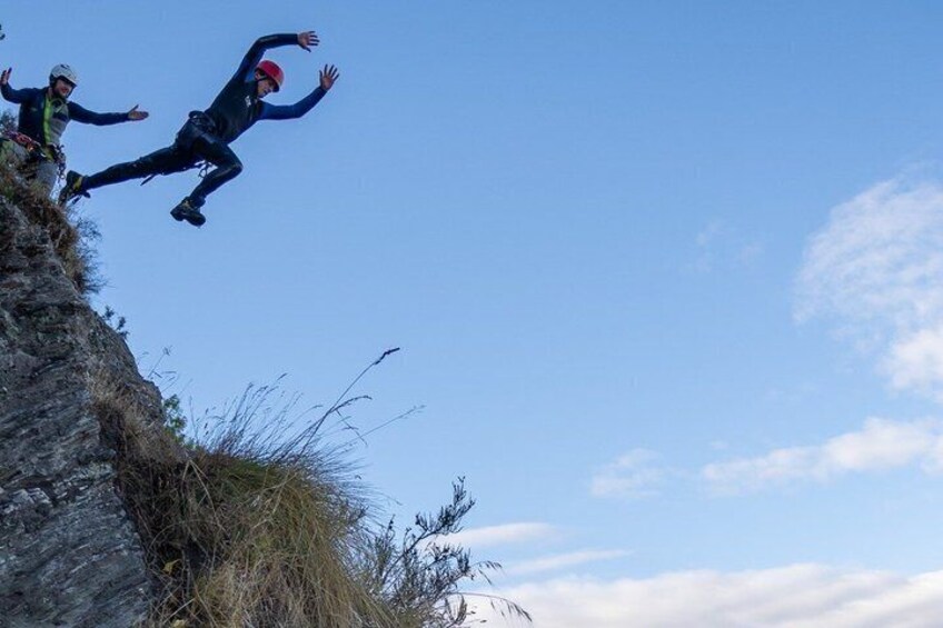 Two individuals jumping off a cliff into the air. 2