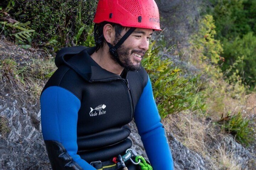 A person wearing a helmet and a blue and black jacket with a logo, sitting outdoors. 3
