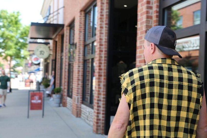 A person walking on a sidewalk, a brick building, and a street sign. 5