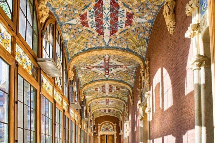 A long corridor with ornate stained glass windows and a colorful ceiling. 2