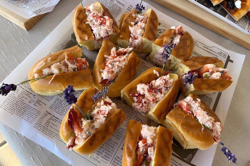 A plate of lobster rolls with a newspaper underneath. 5