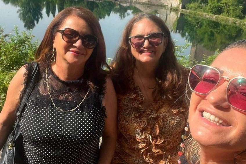 Three people standing by a body of water with greenery in the background. 3