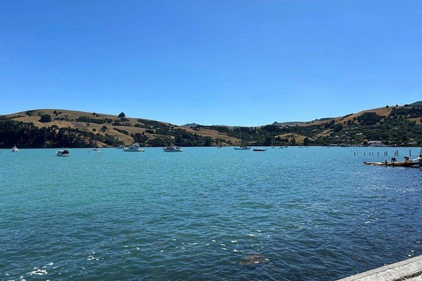 A calm lake with boats, hills, and clear skies. 1