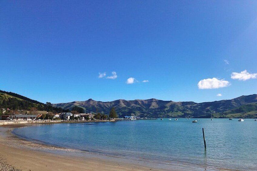 A lake with boats, a sandy beach, and mountains in the background. 3