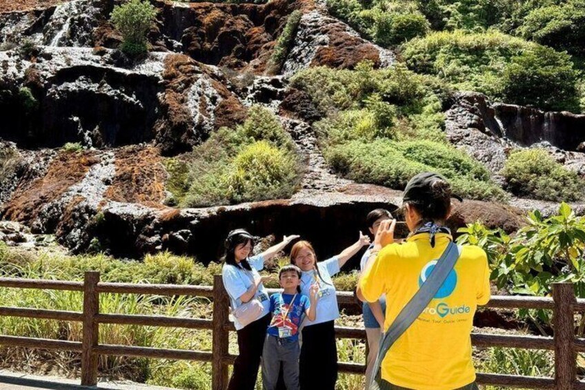 A group of people near a rocky landscape with a fence in the foreground. 1
