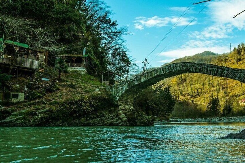 A stone bridge over a river, surrounded by trees and buildings. 4