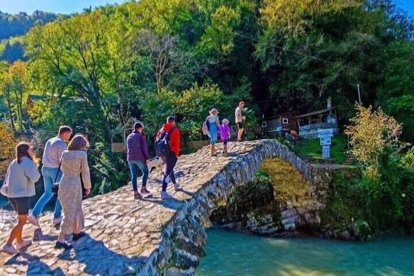 A stone bridge over a river with people walking on it. 1