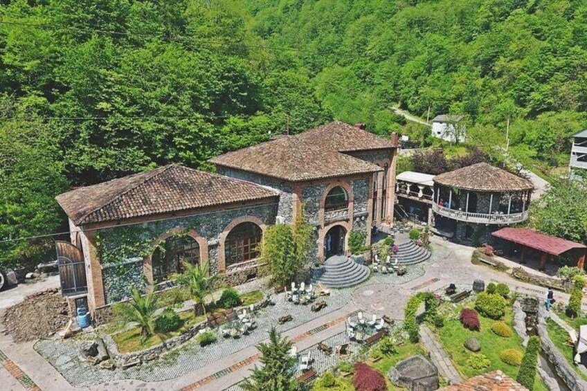 A large building with a tiled roof, arched windows, and a surrounding garden. 2