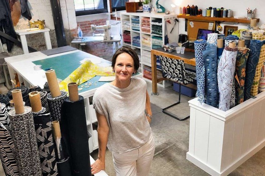 A person standing in a fabric store with rolls of patterned fabric and a sewing machine in the background. 2