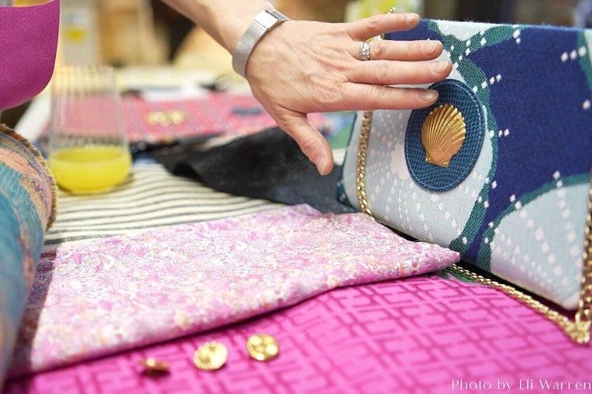 A hand holding a patterned fabric item with a shell design. 5