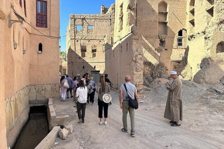 A group of people walking through a narrow alley with old buildings on either side. 4
