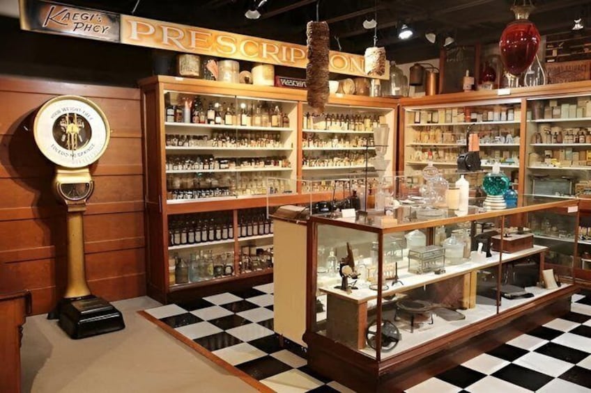 A vintage pharmacy interior with wooden shelves, a checkered floor, and a vintage scale. 1