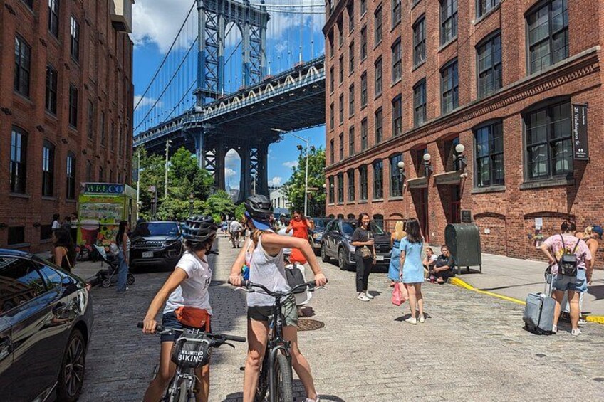 Cyclists on a city street, a bridge, and brick buildings. 3