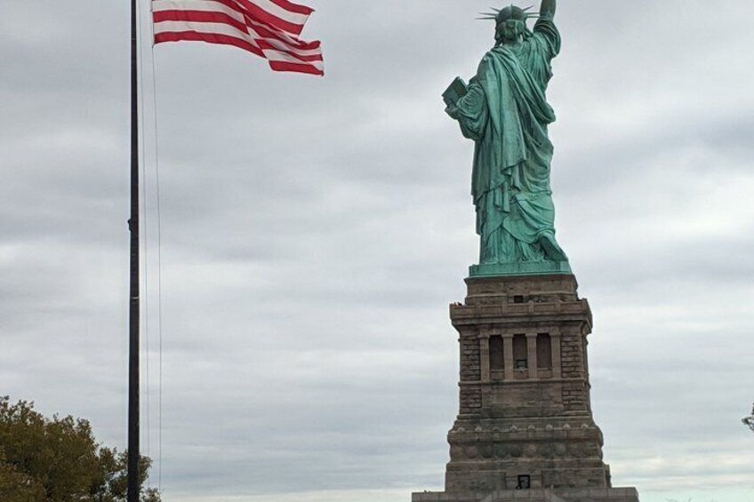 The Statue of Liberty with the American flag waving in the wind. 1