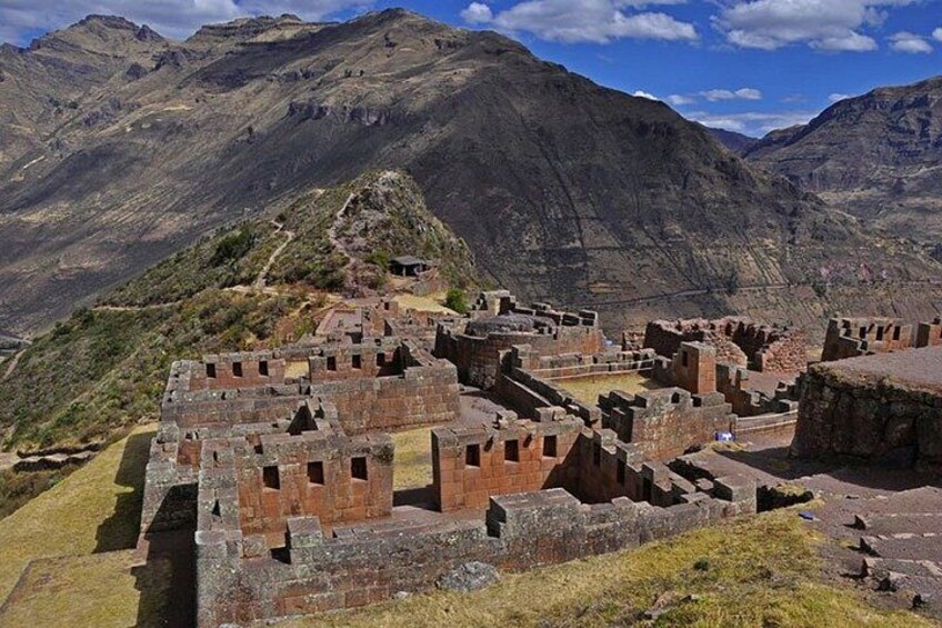 Ancient ruins with stone walls and structures, set against a mountainous backdrop. 4
