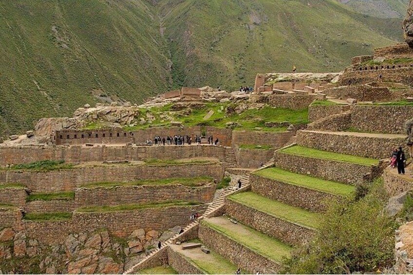 A historical site with terraced stone structures, a pathway, and a mountainous backdrop. 3