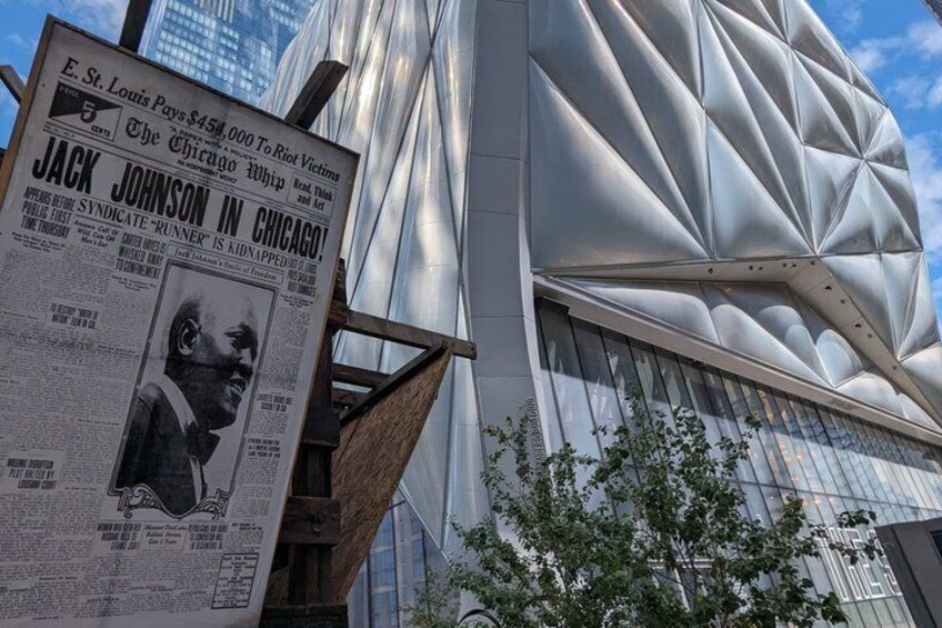 A modern building with a unique geometric facade and a newspaper advertisement. 1
