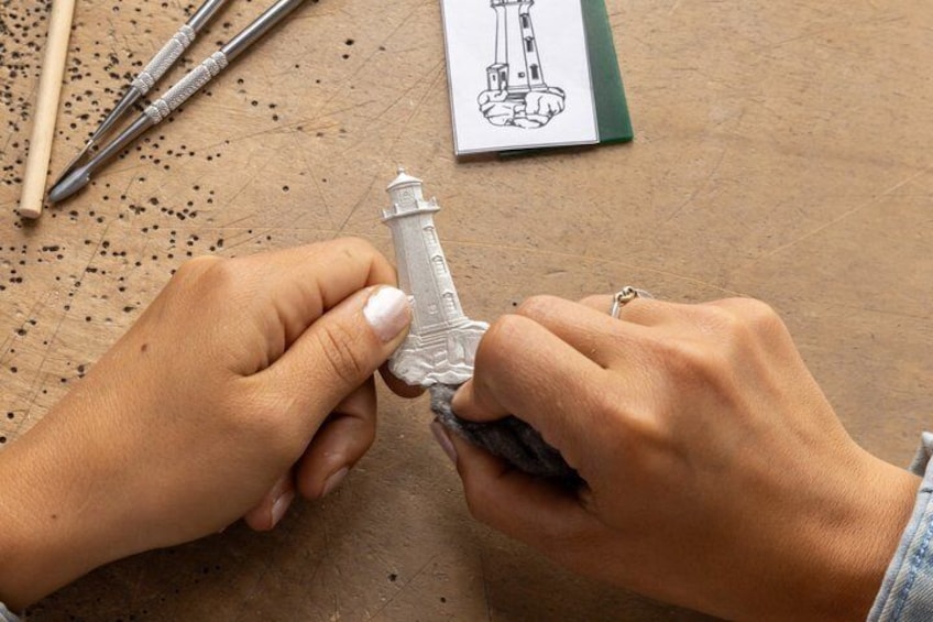 Hands working on a detailed model of a lighthouse. 5