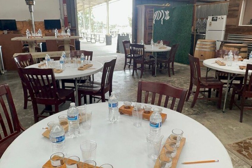 A restaurant with round tables, chairs, and bottles of water. 2