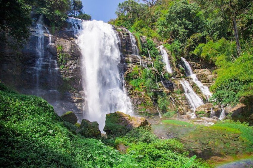 A waterfall cascading down a rocky cliff surrounded by lush greenery. 2