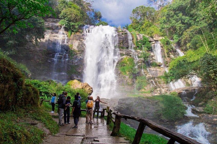 A waterfall, a group of people, and a wooden bridge. 3