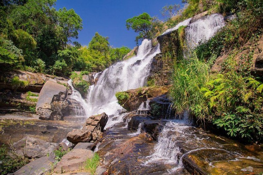 A waterfall cascading over rocks surrounded by lush greenery. 4