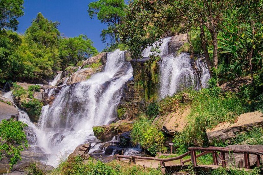A waterfall cascading over rocks surrounded by lush greenery. 5