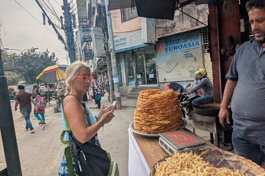 A street vendor selling fried snacks, a woman using a mobile phone, and a shop named 'Euroasia' in the background. 3